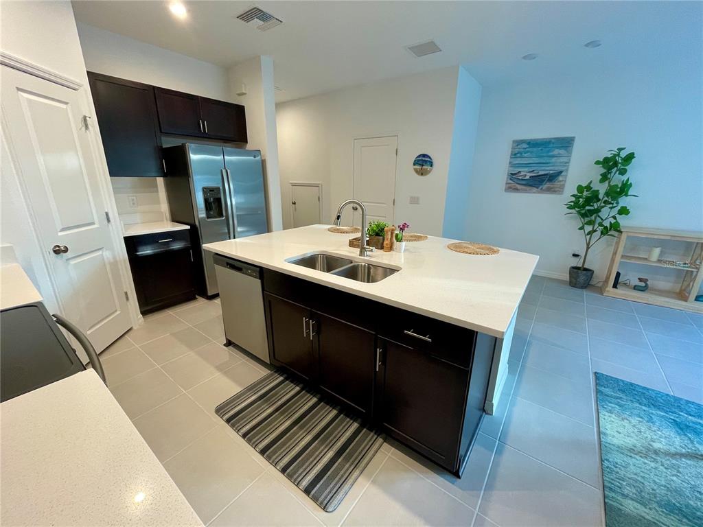 A kitchen features a large white island with a sink, dark cabinetry, and tile flooring — 6417 FAIRMONT LANE, PALMETTO, FL