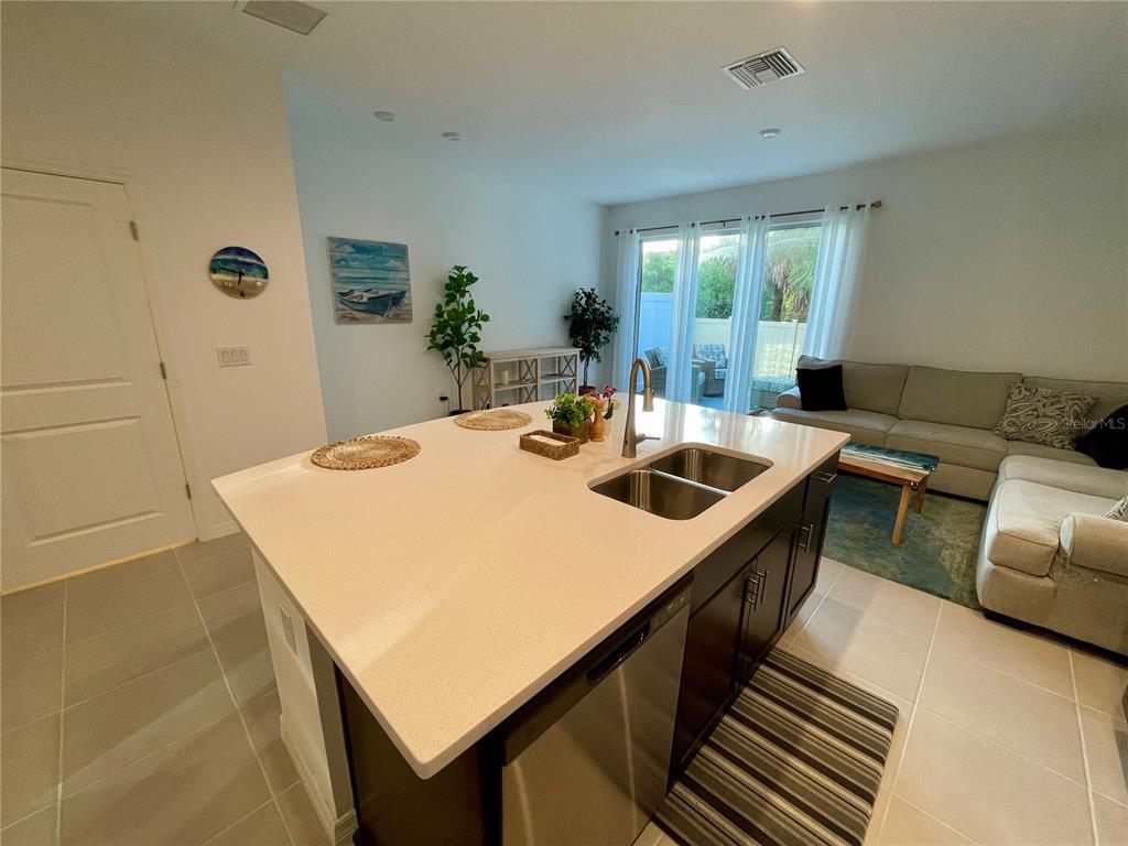 A kitchen island with a sink sits in front of a living room with a sofa — 6417 FAIRMONT LANE, PALMETTO, FL