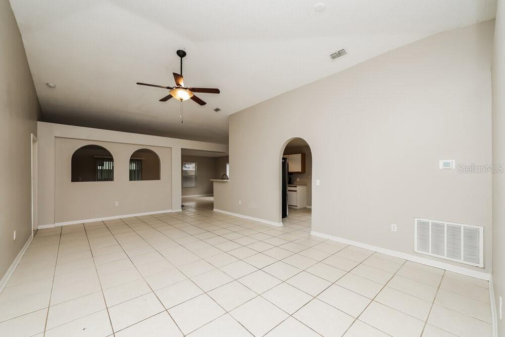 An empty living room features light-colored tile flooring, beige walls, and an arched doorway — 12814 LAKE VISTA DRIVE, GIBSONTON, FL