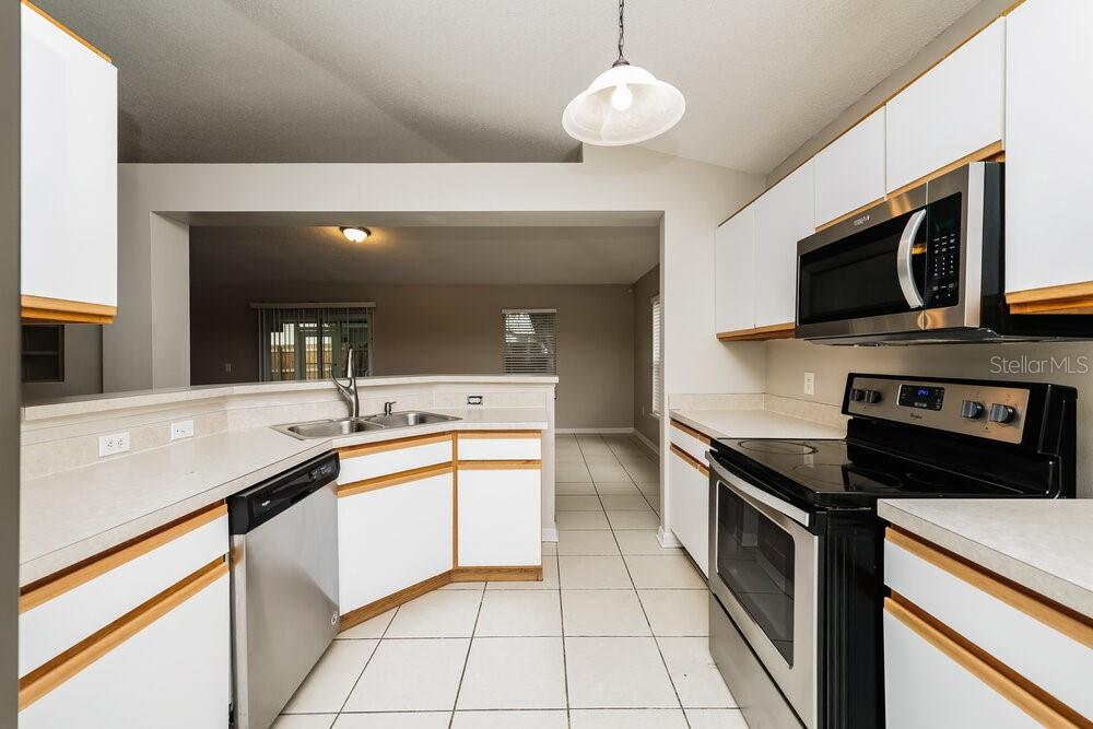 A kitchen with white cabinets, light countertops, stainless steel appliances, and tile flooring — 12814 LAKE VISTA DRIVE, GIBSONTON, FL