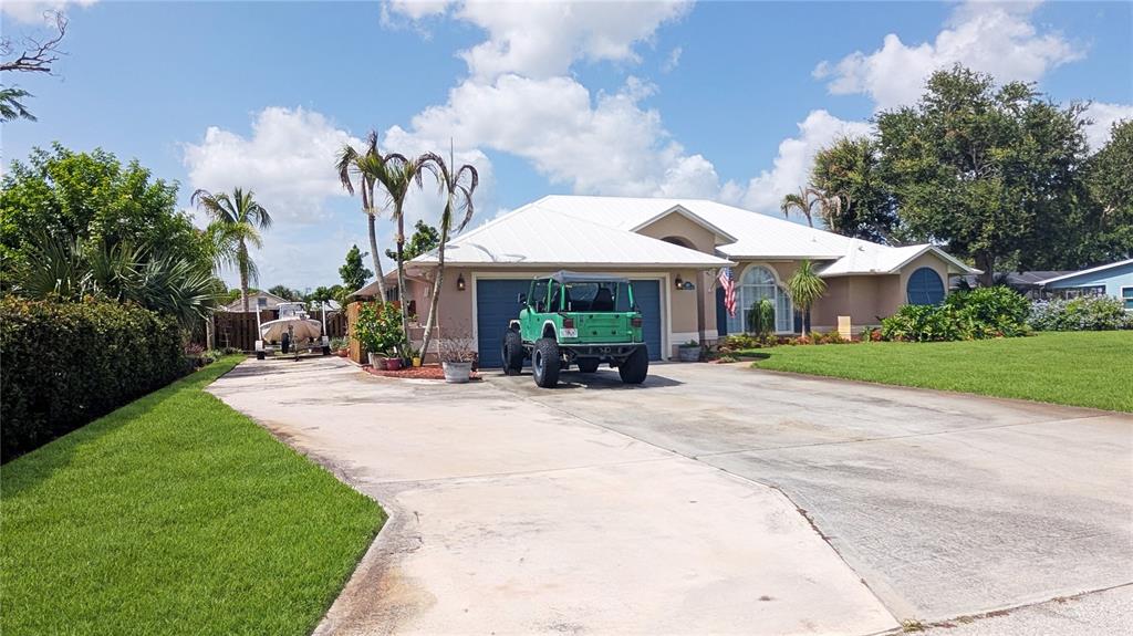 A single-story house with a white metal roof, a green Jeep, and a boat trailer — 114 N 19TH CIRCLE SW, VERO BEACH, FL