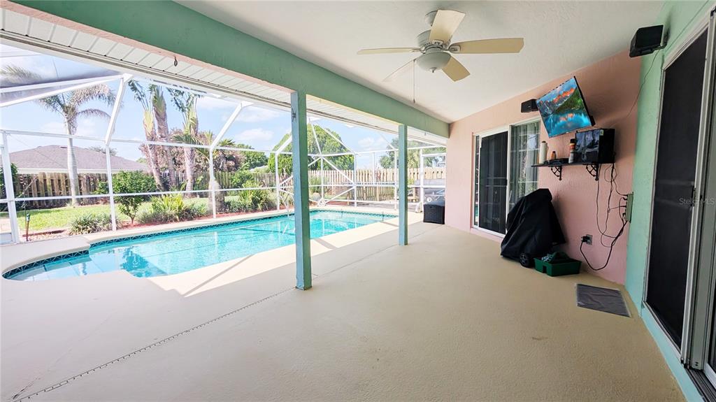 A backyard view of a house with a screened-in pool enclosure and a grassy lawn — 114 N 19TH CIRCLE SW, VERO BEACH, FL