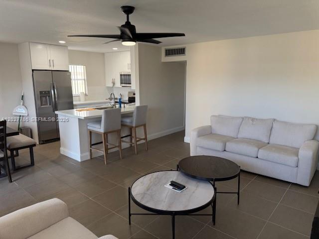 An open-concept living room and kitchen feature a white sofa, island seating, and tile flooring — 417 Brittany I # 417, Delray Beach FL 33446, DELRAY BEACH, FL