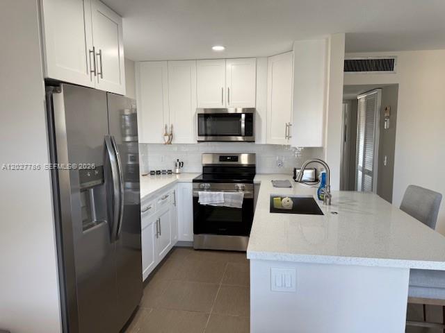 A modern kitchen features white cabinets, stainless steel appliances, and a quartz-topped island — 417 Brittany I # 417, Delray Beach FL 33446, DELRAY BEACH, FL