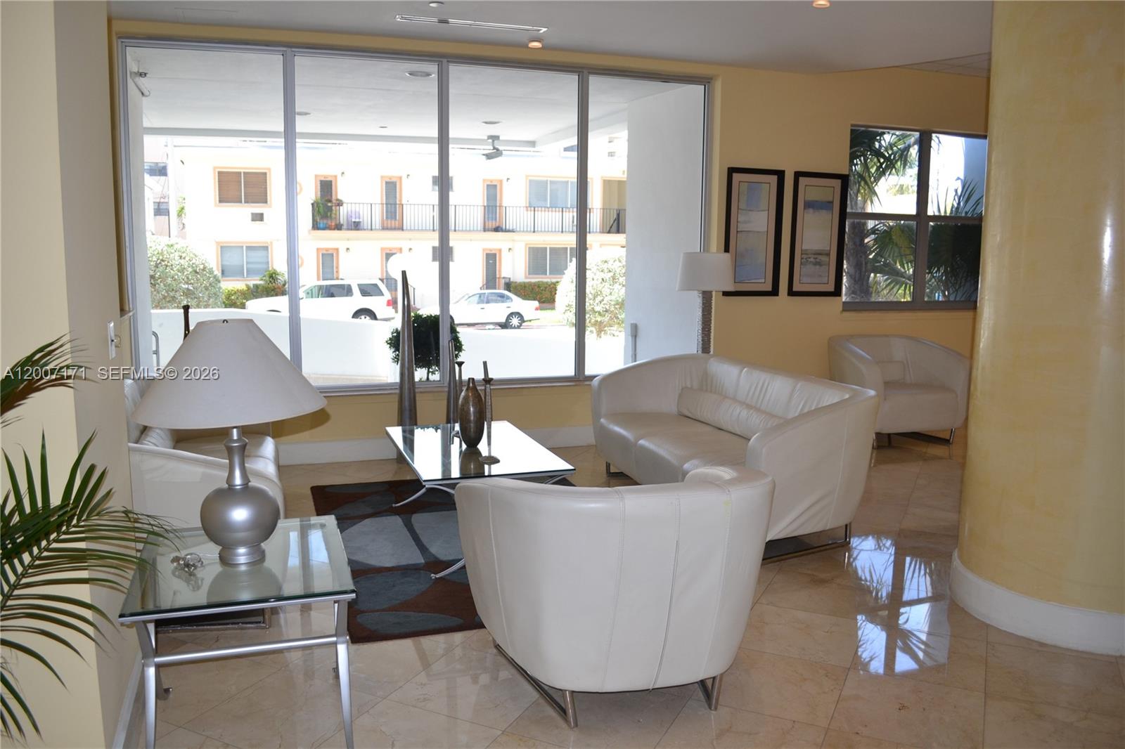 A bright lobby features white leather seating, a glass coffee table, and large floor-to-ceiling windows — 401 69th St # 1013, Miami Beach FL 33141, MIAMI BEACH, FL