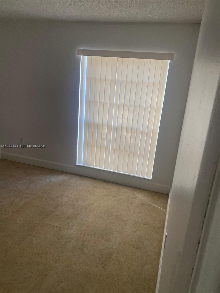 A two-story peach-colored apartment building features a central arched entryway and private parking spaces — 7201 Miami Lakes Dr # B14, Miami Lakes FL 33014, MIAMI LAKES, FL