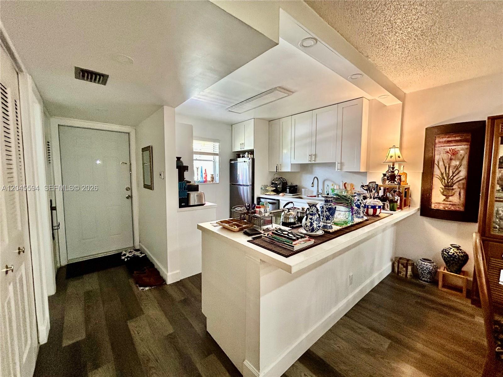 A kitchen features white cabinets, a breakfast bar, and wood-look flooring — 201 Berkley Rd # 104, Hollywood FL 33024, HOLLYWOOD, FL