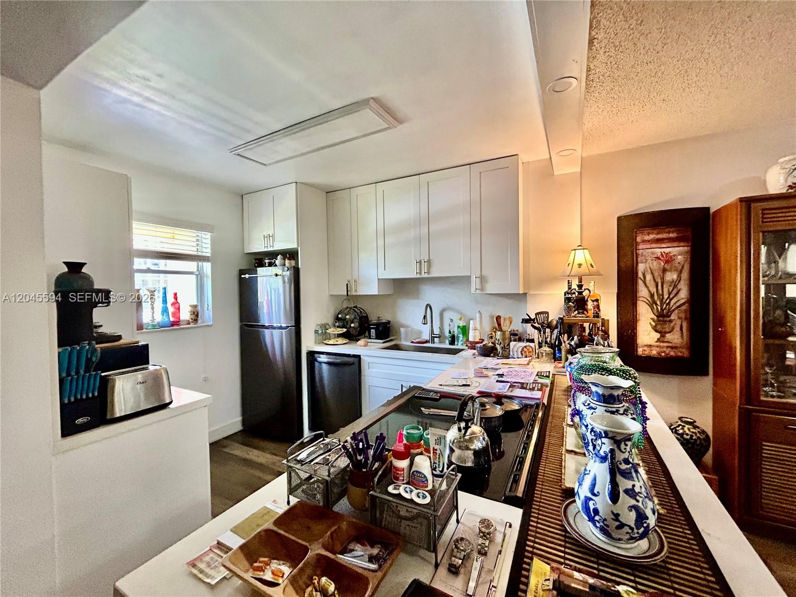 A kitchen features white cabinets, stainless steel appliances, and a central island with decorative pitchers — 201 Berkley Rd # 104, Hollywood FL 33024, HOLLYWOOD, FL