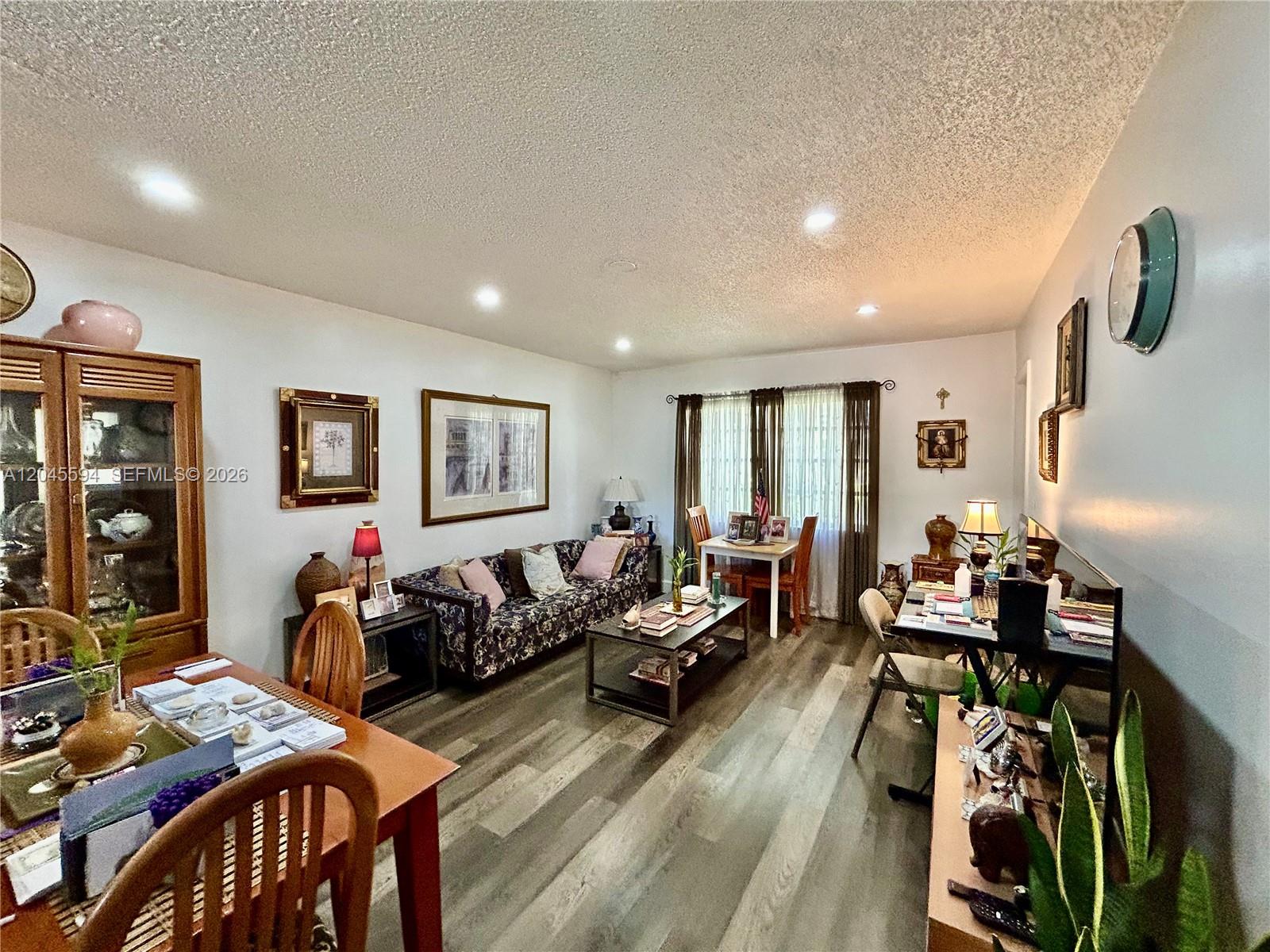 A living and dining area features wood-look flooring, a floral sofa, and a dining table — 201 Berkley Rd # 104, Hollywood FL 33024, HOLLYWOOD, FL