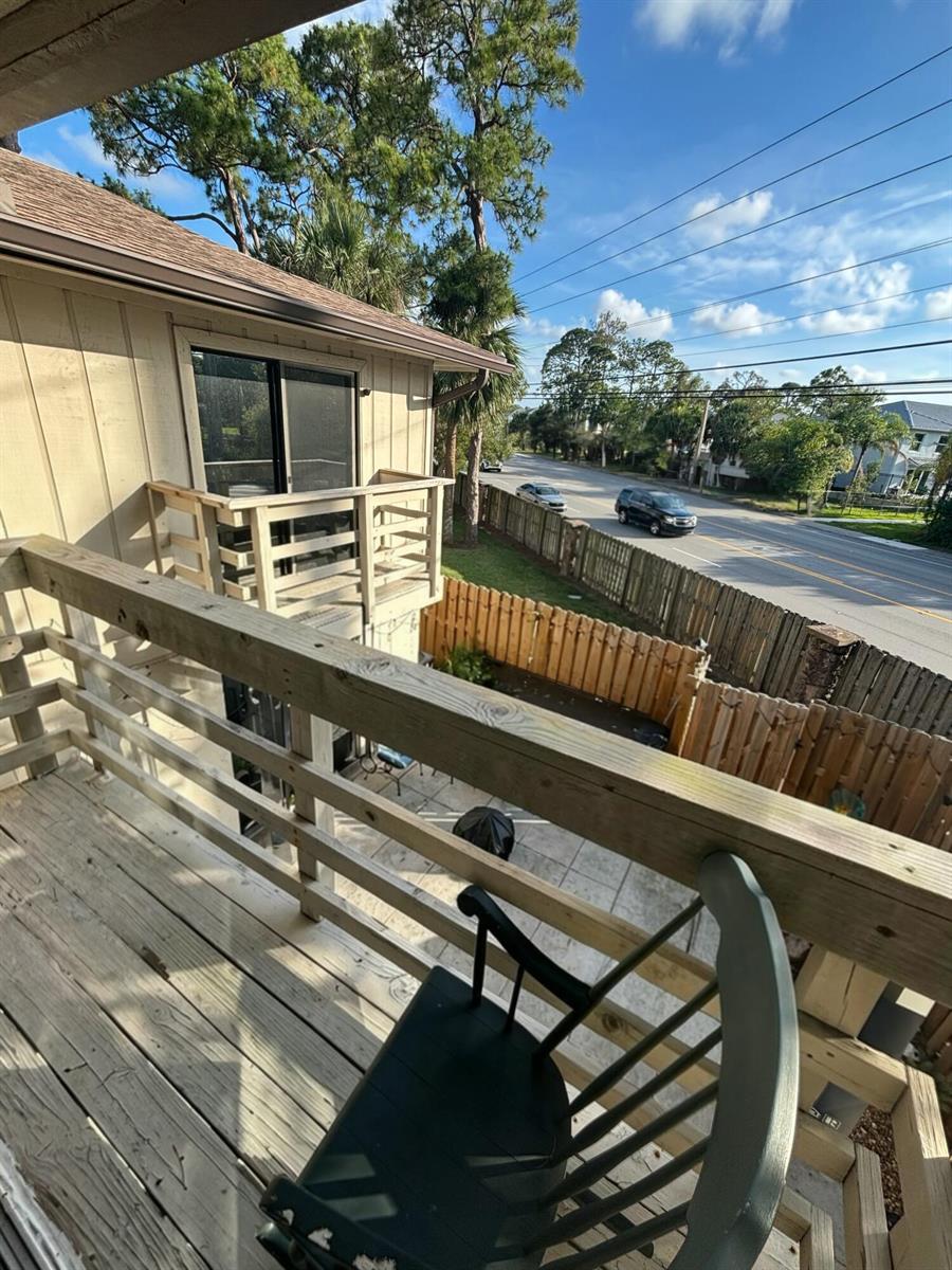 A wooden balcony overlooks a fenced backyard and a street with passing vehicles — 2811 Stoneway Lane # B, Fort Pierce FL 34982, FORT PIERCE, FL