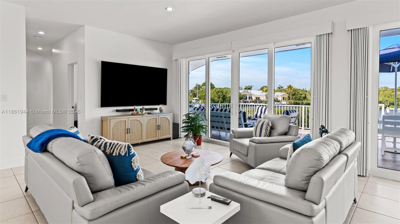 A bright living room features light gray leather furniture, a wooden console, and sliding glass doors — 7760 Aviation BLvd. # 0, Marathon FL 33050, MARATHON, FL