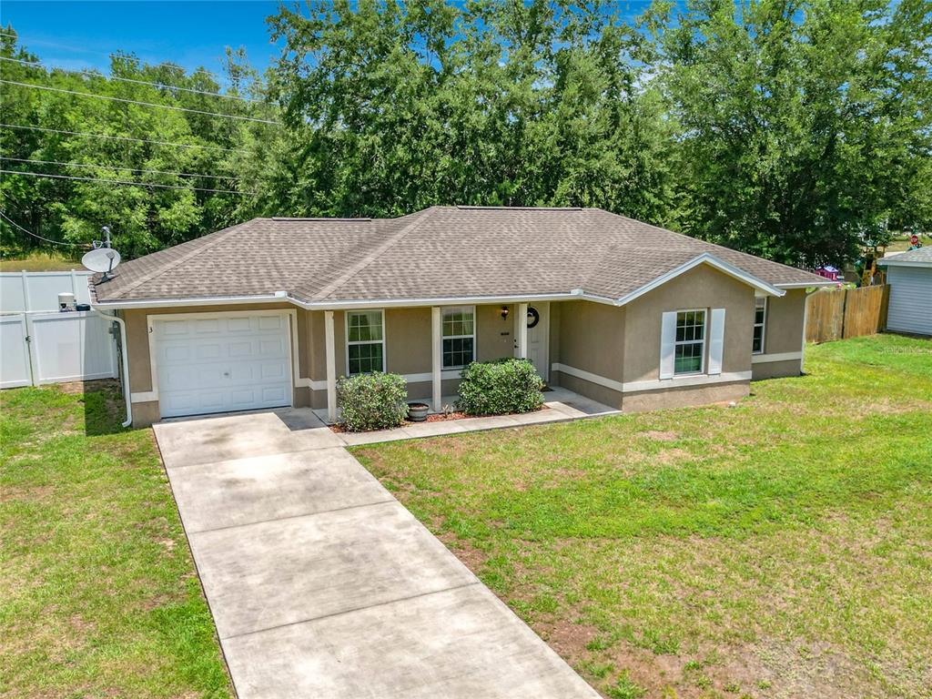 A single-story house with a tan stucco exterior, a shingled roof, and a concrete driveway — 3 PINE TRACK PLACE, OCALA, FL