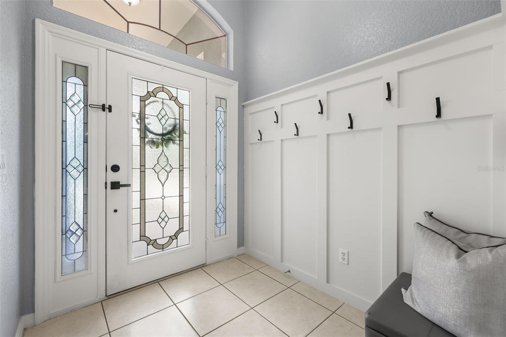 An entryway features a white front door with glass panels, tile flooring, and wall paneling — 961 MARISA LANE, KISSIMMEE, FL