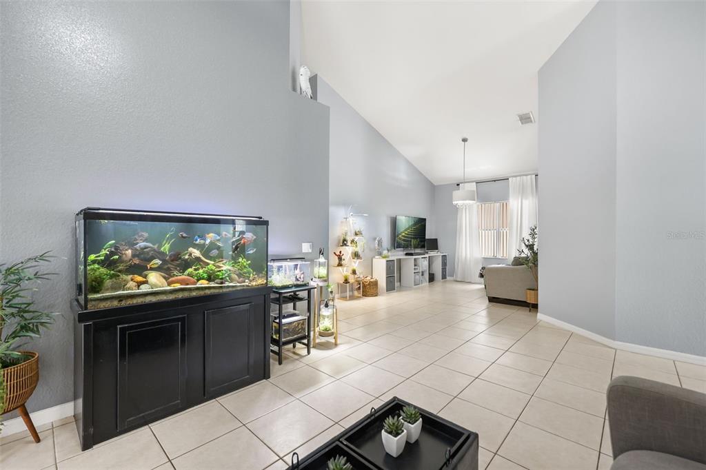 A spacious living room features light gray walls, tile flooring, and a large fish tank — 961 MARISA LANE, KISSIMMEE, FL