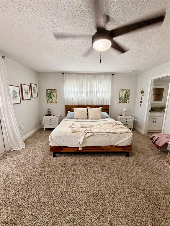 A bedroom features a wooden bed frame, two nightstands, a ceiling fan, and carpeted flooring — 11450 LINDEN DRIVE, SPRING HILL, FL