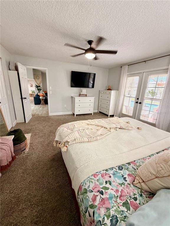 A bedroom features a bed with a floral comforter, a ceiling fan, and French doors — 11450 LINDEN DRIVE, SPRING HILL, FL