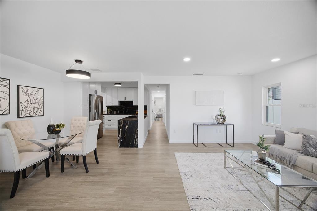 An open-concept living and dining area features light wood flooring, white walls, and modern furniture — 5207 W CLEVELAND STREET, TAMPA, FL