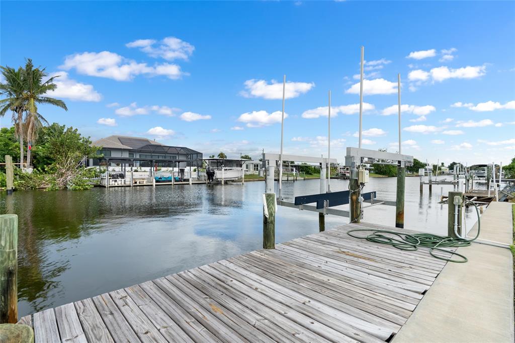 A wooden boat dock with a boat lift overlooks a canal and residential properties — 21748 EDGEWATER DRIVE, PORT CHARLOTTE, FL