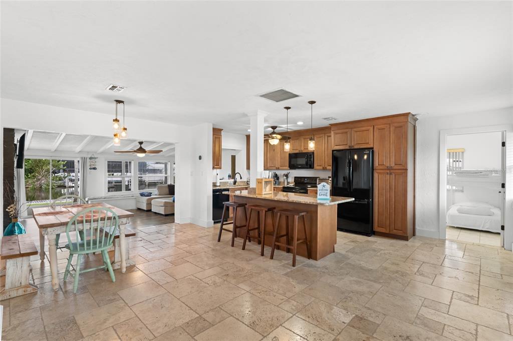 An open-concept kitchen and dining area features tile flooring, wood cabinets, and a granite island — 21748 EDGEWATER DRIVE, PORT CHARLOTTE, FL