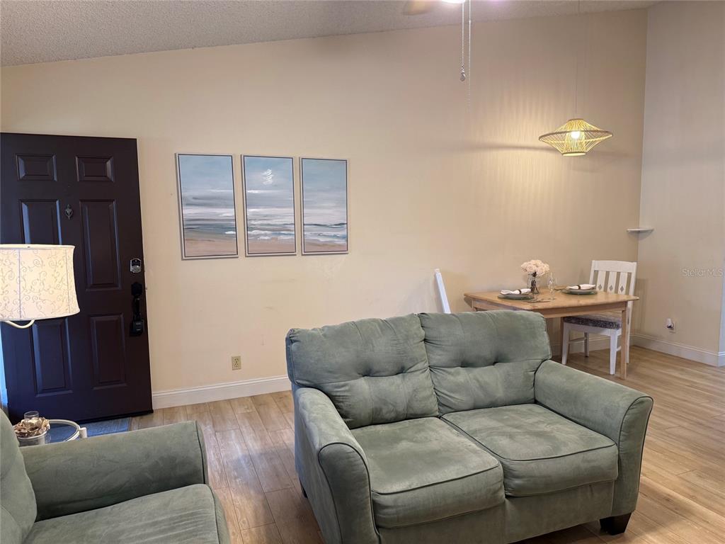 A living room features a green loveseat, a dining table, and a dark front door — 1711 HAMMOCK PINE BOULEVARD UNIT 1711, CLEARWATER, FL