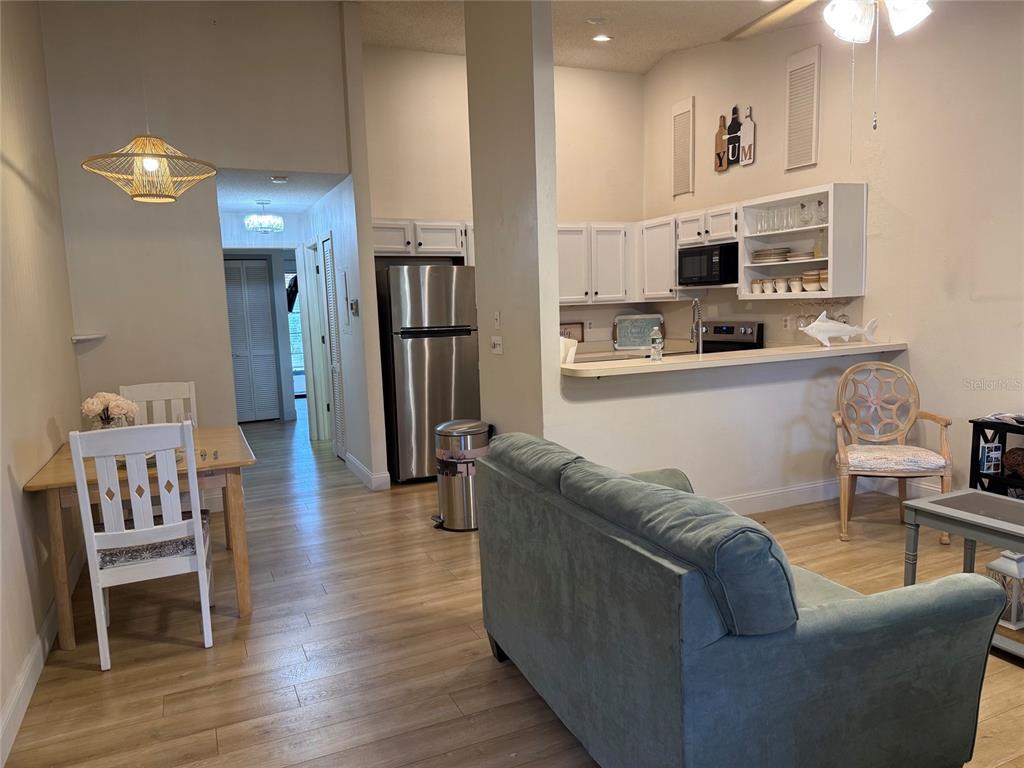 A kitchen with white cabinets and stainless steel appliances overlooks a living and dining area — 1711 HAMMOCK PINE BOULEVARD UNIT 1711, CLEARWATER, FL