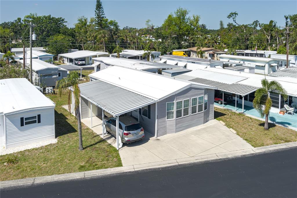 An elevated view shows a gray manufactured home with a carport and a concrete driveway — 3309 BERNADETTE DRIVE, ELLENTON, FL