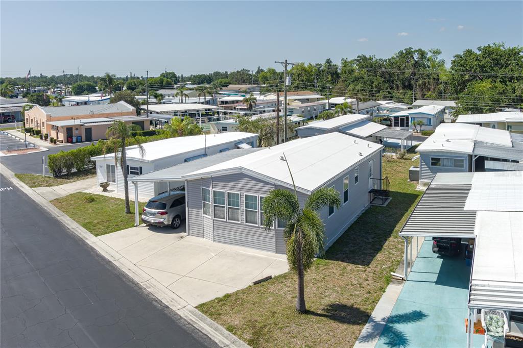 An elevated view of a light gray manufactured home with a carport and palm tree — 3309 BERNADETTE DRIVE, ELLENTON, FL