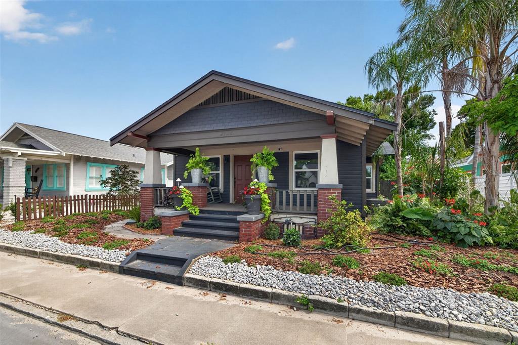 A dark-painted bungalow with a brick-based front porch, steps, and landscaping under a blue sky — 2128 5TH AVENUE N, ST PETERSBURG, FL