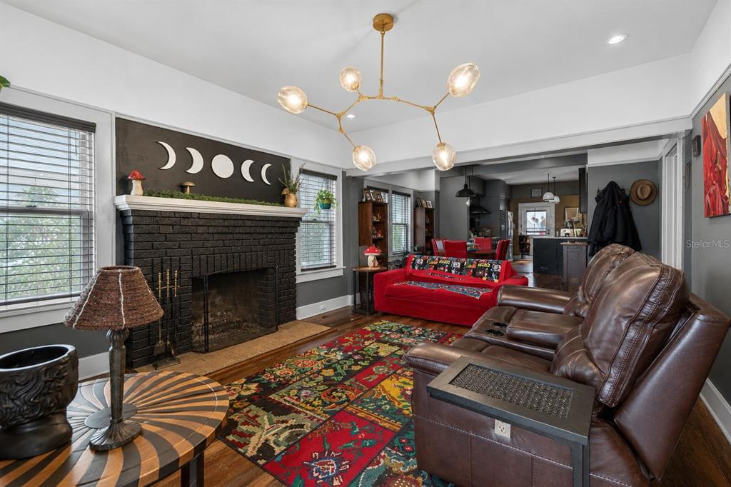 A living room features a black brick fireplace, a colorful patterned rug, and brown leather furniture — 2128 5TH AVENUE N, ST PETERSBURG, FL