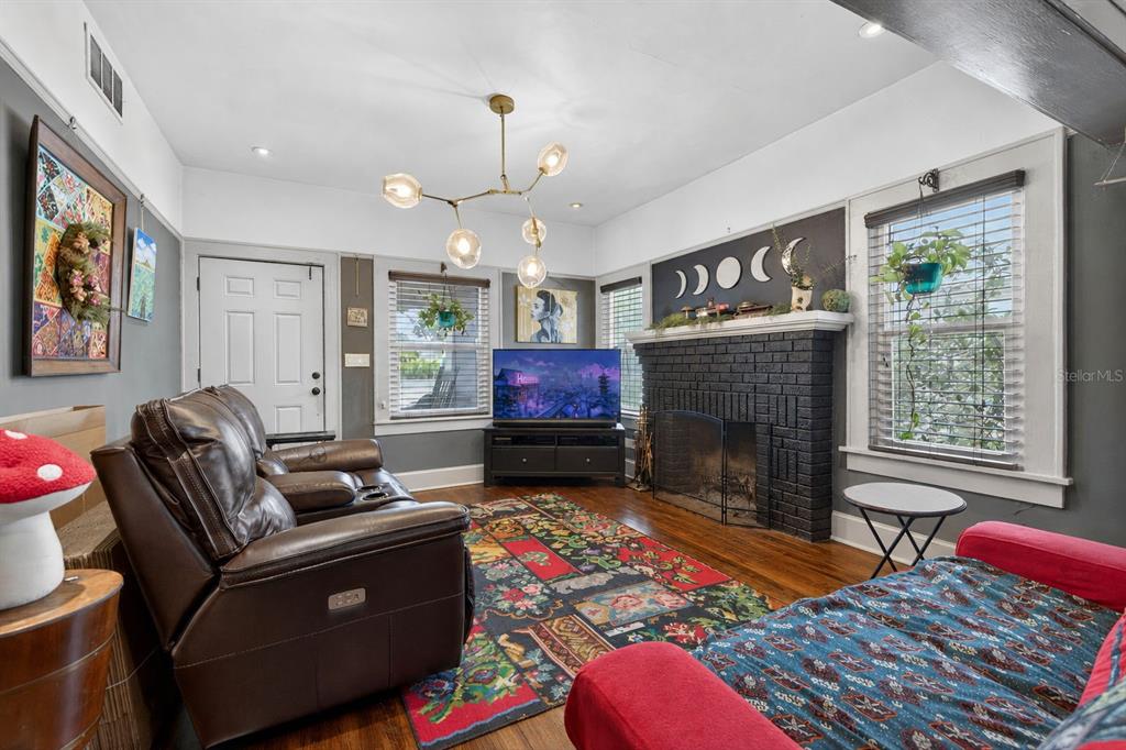 A living room features a black brick fireplace, a colorful rug, and a modern chandelier — 2128 5TH AVENUE N, ST PETERSBURG, FL