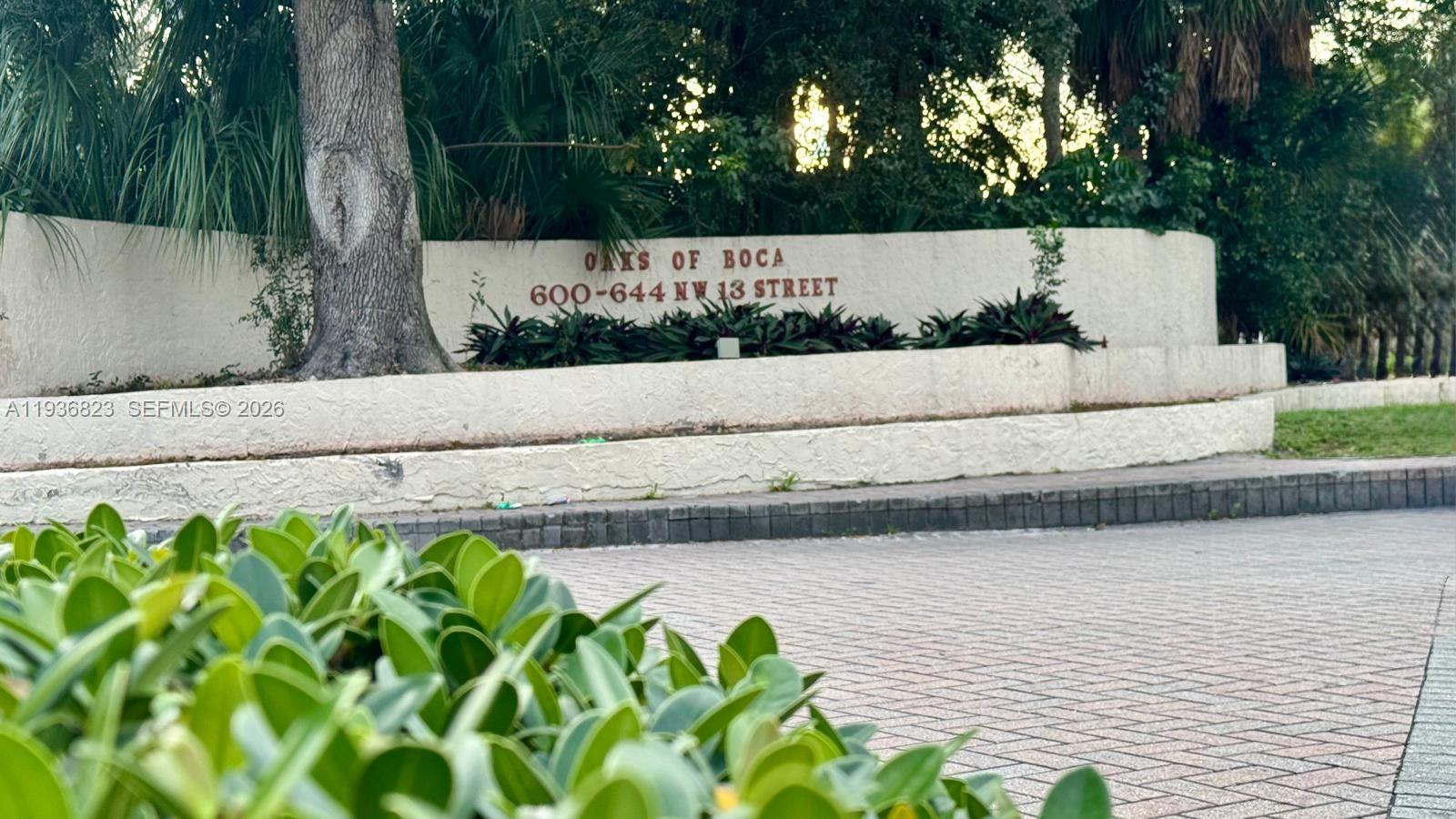 A curved stucco sign displays the name of a residential community near a paved driveway — 636 NW 13th St # 0230, Boca Raton FL 33486, BOCA RATON, FL