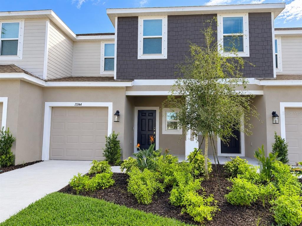 The exterior of a two-story townhouse features a garage, a front entrance, and landscaping — 15144 CUZCORRO COURT, NOKOMIS, FL