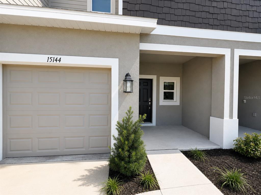 A beige house exterior features a garage, a covered entryway, and a small front garden — 15144 CUZCORRO COURT, NOKOMIS, FL
