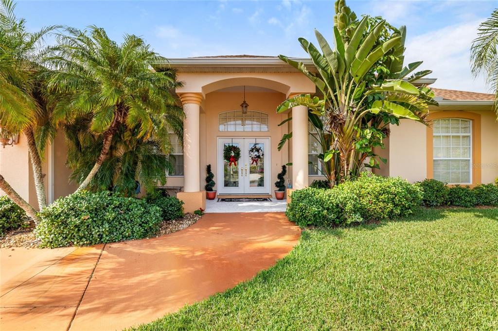 The exterior of a peach-colored house features a covered entryway with columns and double doors — 245 ROTONDA BOULEVARD N, ROTONDA WEST, FL