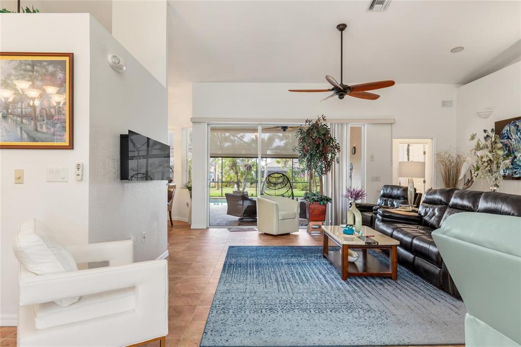 A living room features a blue area rug, leather sofa, white armchairs, and sliding glass doors — 245 ROTONDA BOULEVARD N, ROTONDA WEST, FL