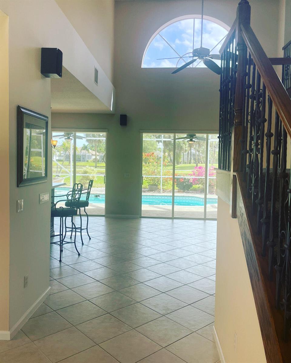A view from a staircase looking toward a living area with tile floors and pool access — 7754 Monarch Court, Delray Beach FL 33446, DELRAY BEACH, FL
