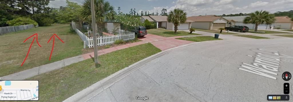A vacant grassy lot sits next to a single-story house with a white picket fence — POLYNESIAN ISLE BOULEVARD, KISSIMMEE, FL