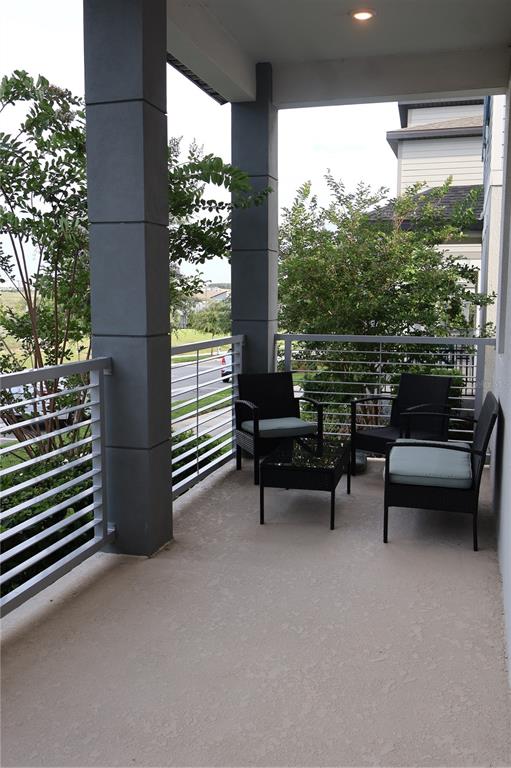 A covered balcony features gray columns, a metal railing, and a small outdoor seating set — 4958 CITRUS LEAF BLVD, WINTER GARDEN, FL