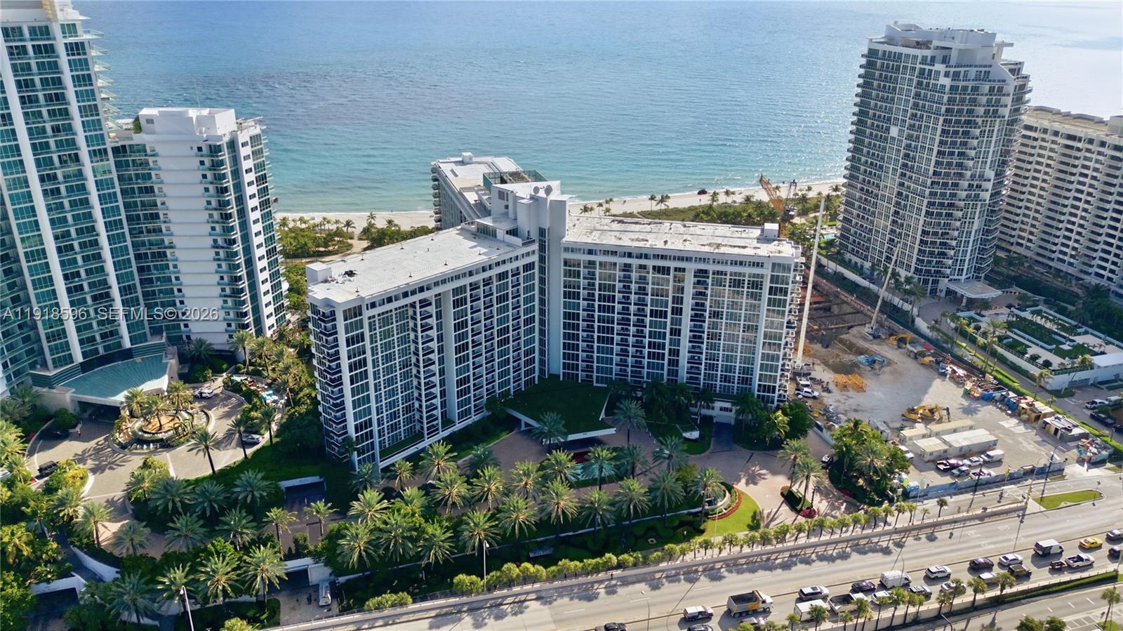 An aerial view shows a large beachfront apartment complex surrounded by palm trees and construction — 10275 Collins Avenue # 1101, Bal Harbour FL 33154, BAL HARBOUR, FL