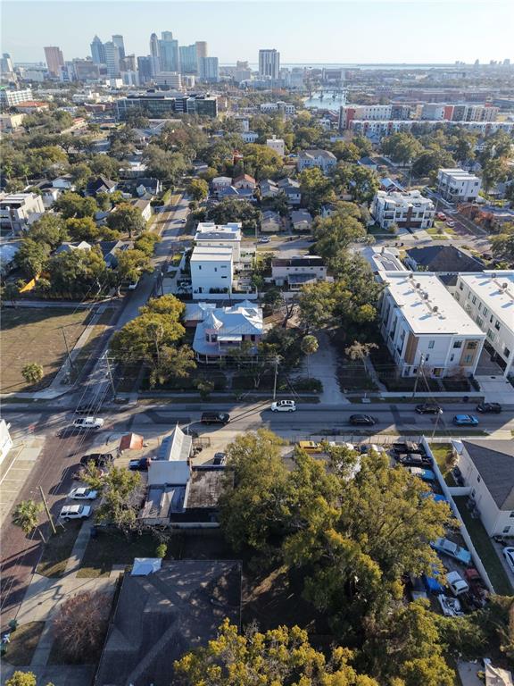 An aerial view shows a residential neighborhood with houses, trees, and a distant city skyline — 201 W COLUMBUS DRIVE, TAMPA, FL