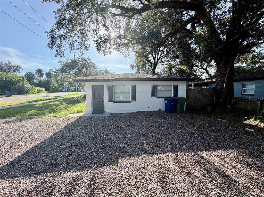 A single-story white house with a gravel driveway and a large tree in the yard — 10123 N 11TH STREET UNIT A, TAMPA, FL