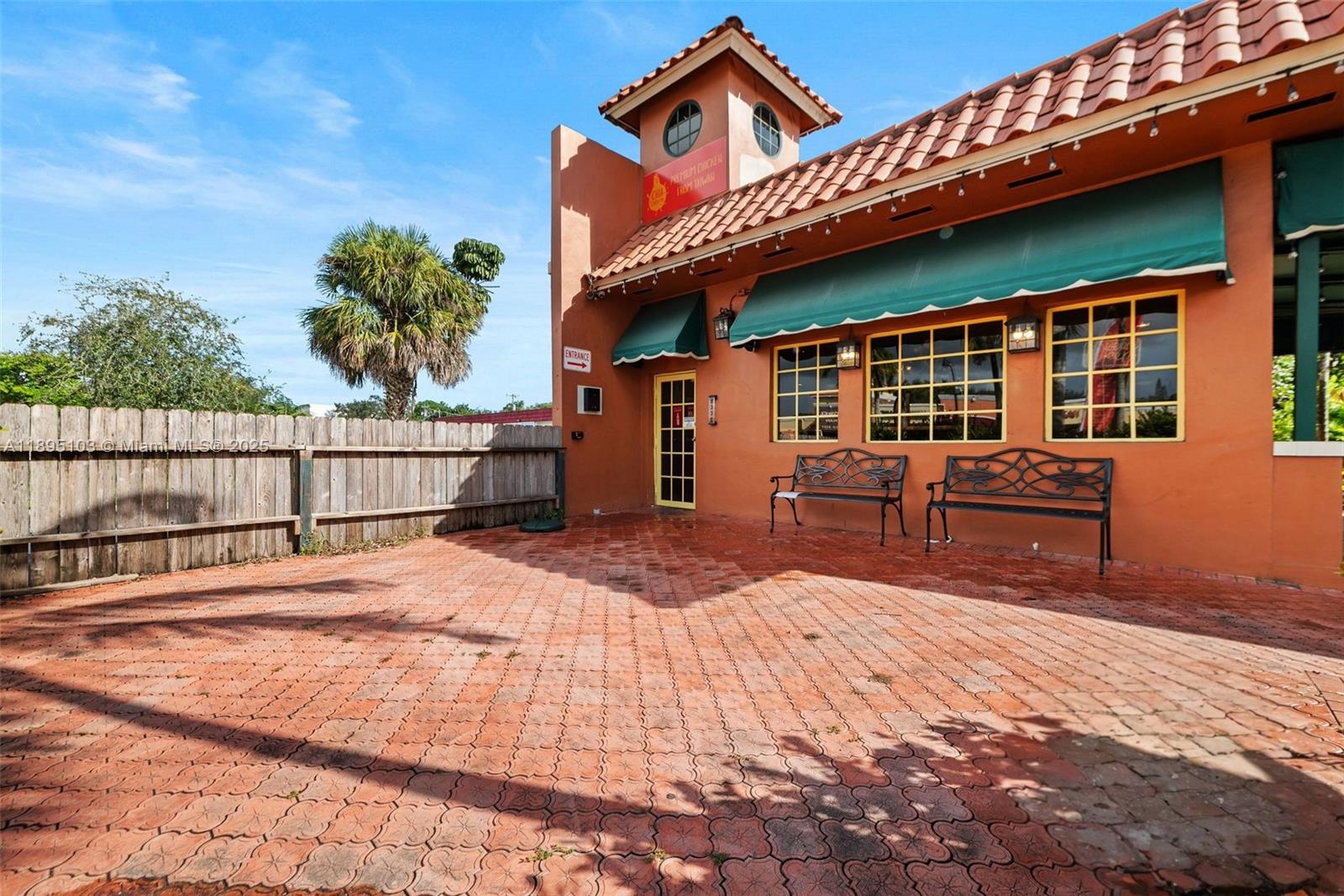 The exterior of a building features a brick patio, two metal benches, and an entrance — 6330 Miramar Pkwy, Miramar FL 33023, MIRAMAR, FL