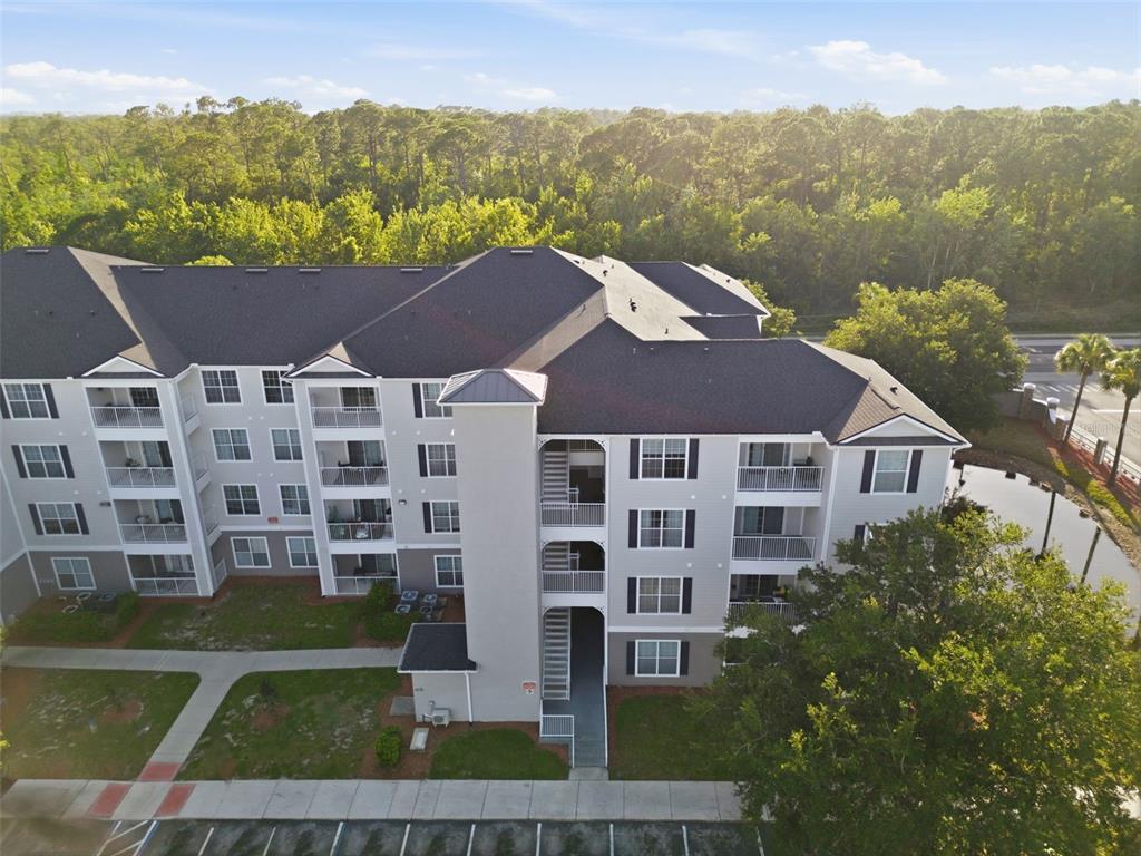 An aerial view of a multi-story apartment building with balconies and a parking lot — 3176 FELTRIM PLACE UNIT 302, KISSIMMEE, FL