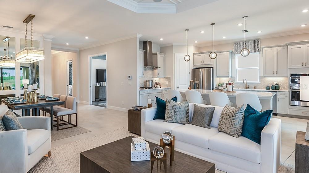 A living room features a television, mirrored console, and dining area with a mirrored wall — 3216 VICENZA COURT, BRADENTON, FL