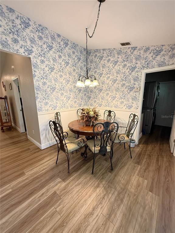 A dining area features a round wooden table, four metal chairs, and blue floral wallpaper — 10 EMERALD TRAIL, OCALA, FL