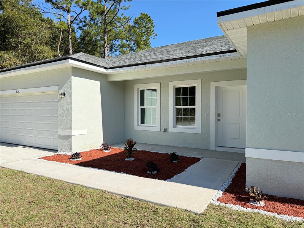 A single-story house exterior features a white garage, two windows, and a front entrance — 6365 SW 156TH STREET, OCALA, FL