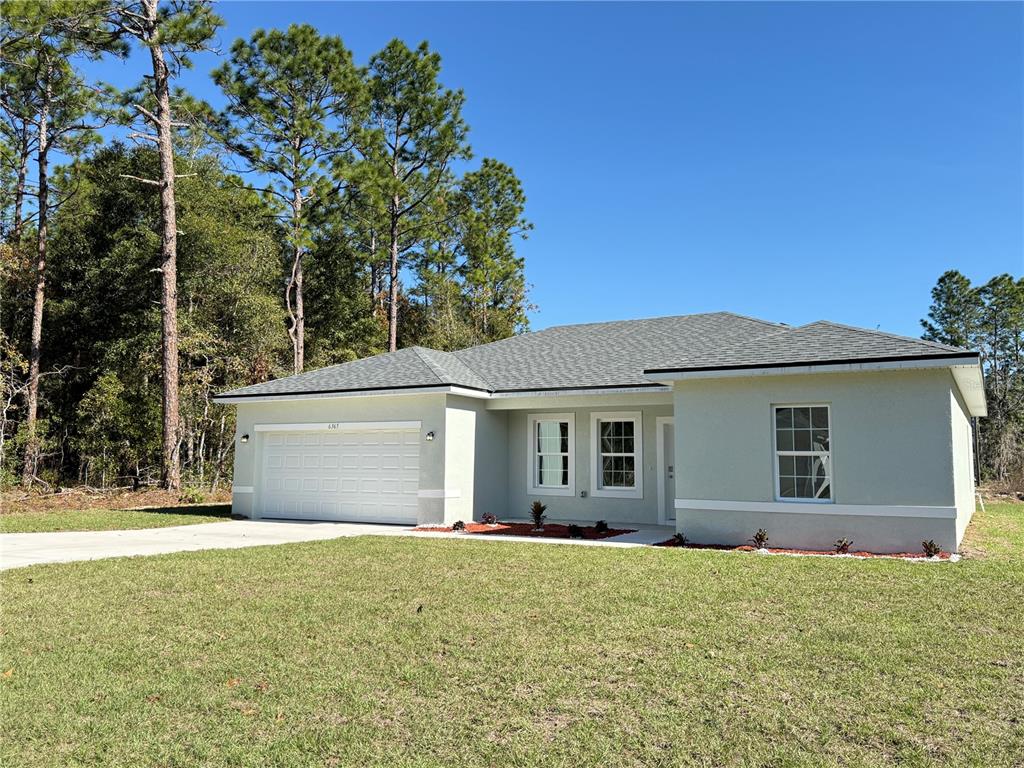 A single-story house with a light-colored stucco exterior, a two-car garage, and a shingled roof — 6365 SW 156TH STREET, OCALA, FL