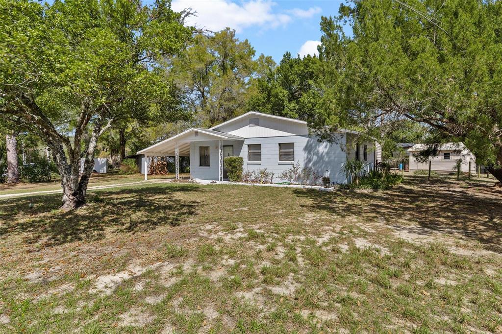 A single-story house with a covered porch and a detached shed sits on a lot — 501 POINSETTIA AVENUE, FRUITLAND PARK, FL