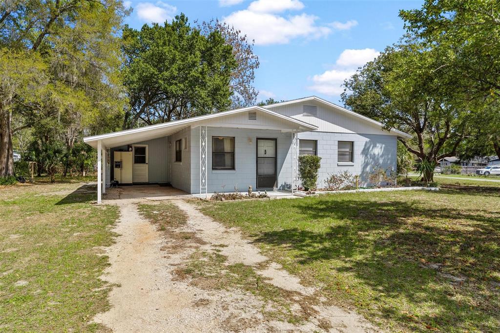 A light blue, single-story house with a carport and a gravel driveway — 501 POINSETTIA AVENUE, FRUITLAND PARK, FL