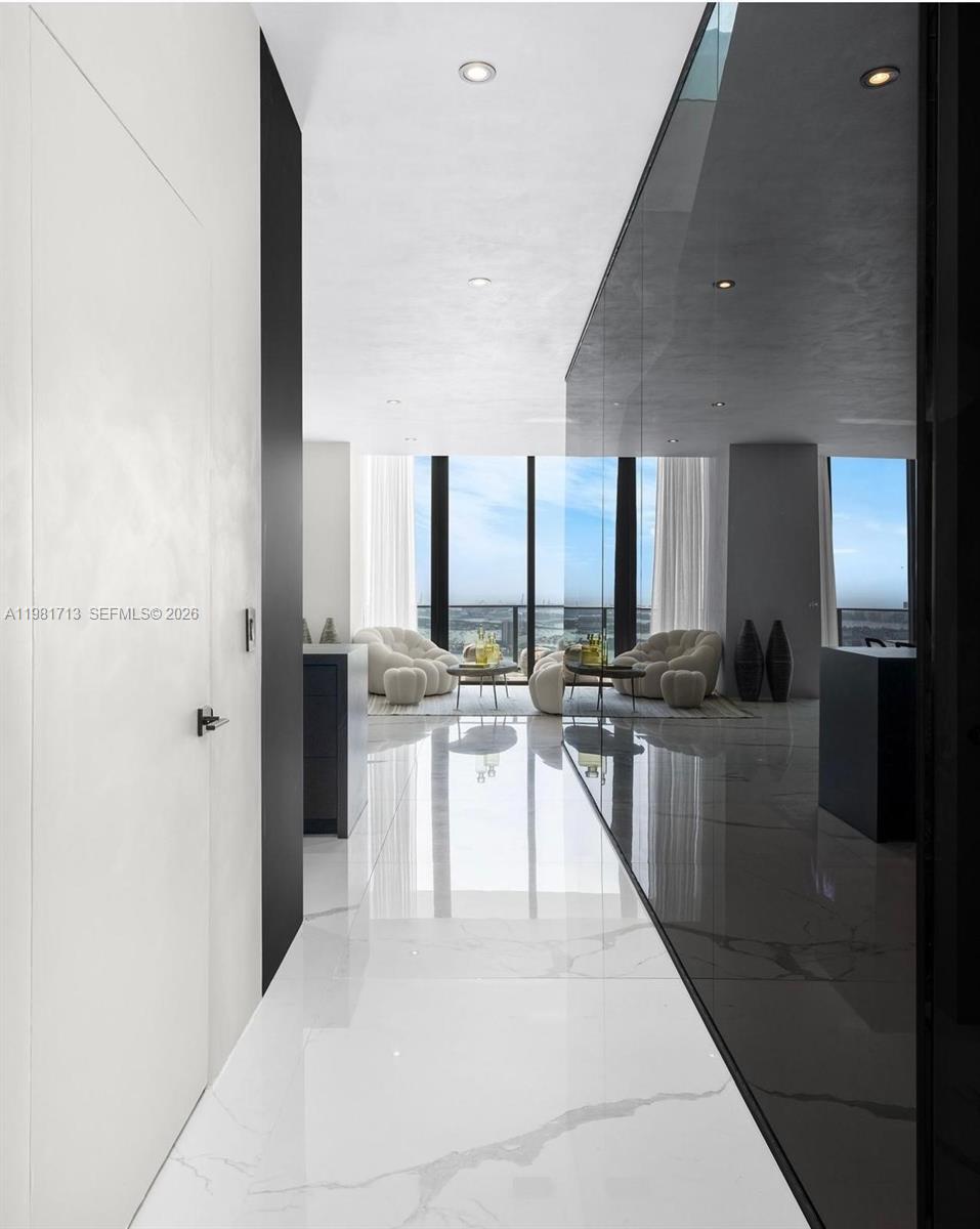 A hallway with white marble floors leads to a living area with floor-to-ceiling windows — 650 NE 32nd St, Miami FL 33137, MIAMI, FL
